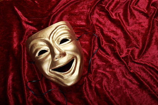 Classical theater comedy mask on a velvet curtain stock photo