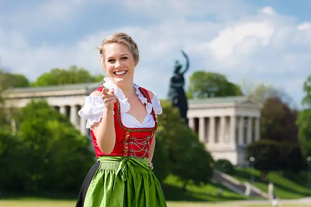 Young woman in traditional Bavarian clothes - dirndl or tracht - in front of Bavaria in Munich