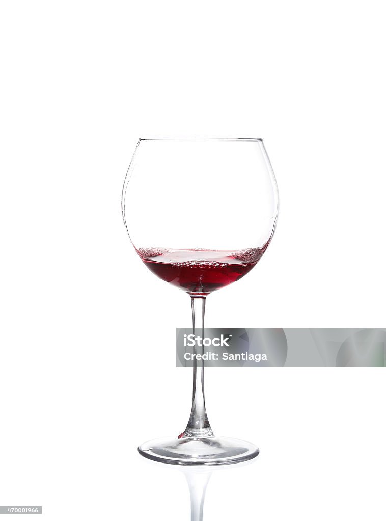 Red wine pouring from bottle into big glass Red wine pouring from bottle into big glass on white background 2015 Stock Photo