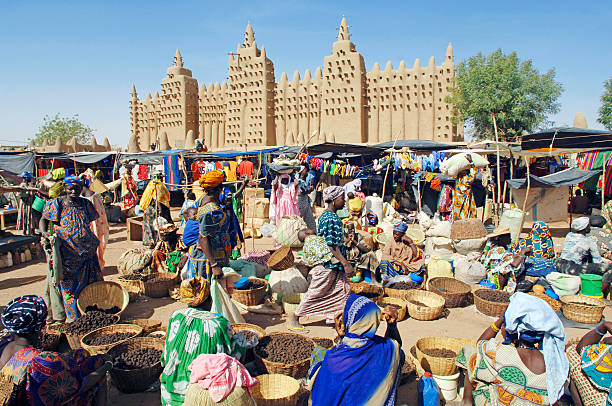 African market Djenne,Mali-March 13th 2006:A busy and colourful market scene in front of the great mud Mosque in the Saharan town of Djenne mali stock pictures, royalty-free photos & images