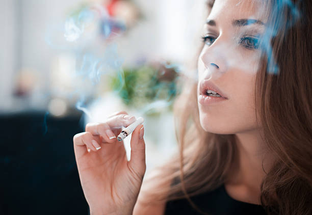The thoughtful woman smokes a cigarette stock photo