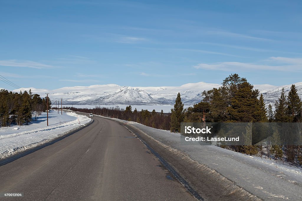 The lonely car A road with an isolated car with some snow covered mountains in the background 2015 Stock Photo