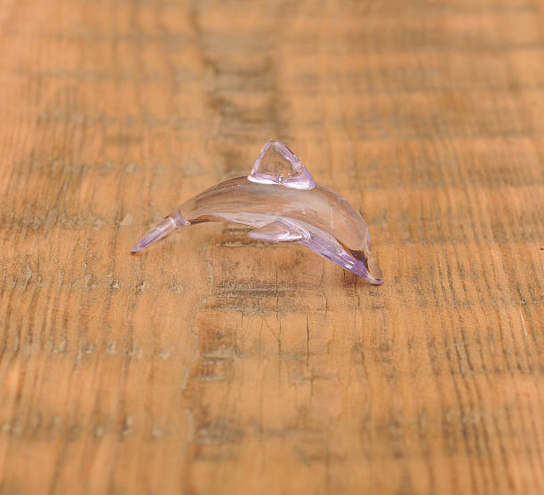 istock closeup toy glass dolphin on wooden background 470015577