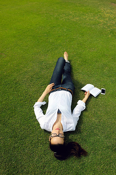 istock Young woman reading a book in the park 470016855