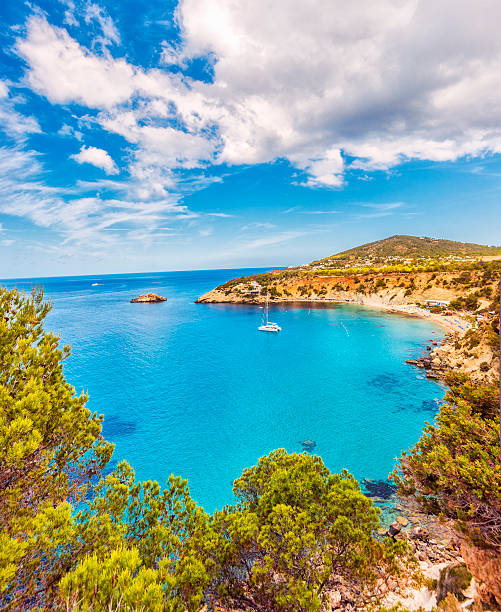 Beautiful view on Cala D'hort on Ibiza Elevated view the beautiful beach, fisherman houses and a catamaran in the bay of Cala D'hort in Ibiza (Spain). balearic islands stock pictures, royalty-free photos & images