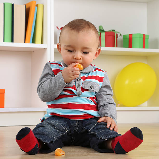 istock Baby child eating mandarin orange fruit 470021448