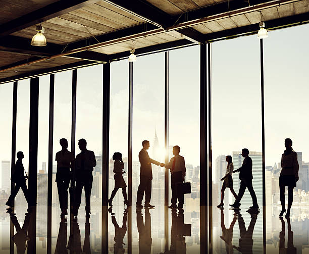 Silhouette businesspeople entering office building Silhouettes of business people walking, talking, and shaking hands with glass windows and a view of a cityscape in the background. mediation photos stock pictures, royalty-free photos & images