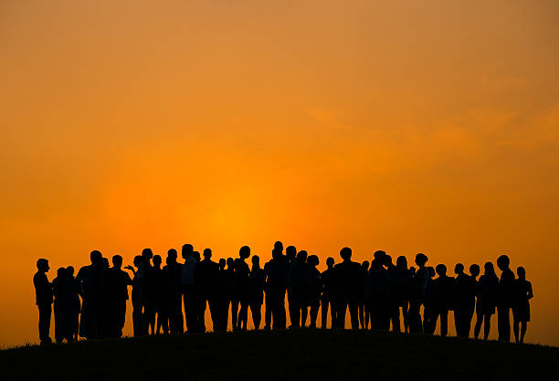 istock Large group of people silhouetted against an orange sunset 470021517