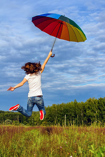 istock Woman jumping with colorful umbrella 470023552