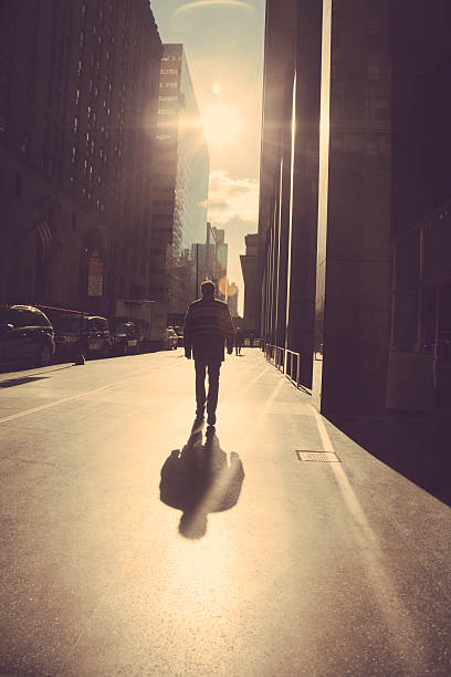 homme marchant sur la rue de la ville de new york sur le lever du soleil - new york city sunrise new york state usa photos et images de collection