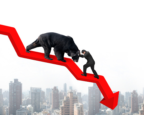 Businessman against black bear on red arrow downward trend line with sky cityscape background. Fight back bearish market concept.