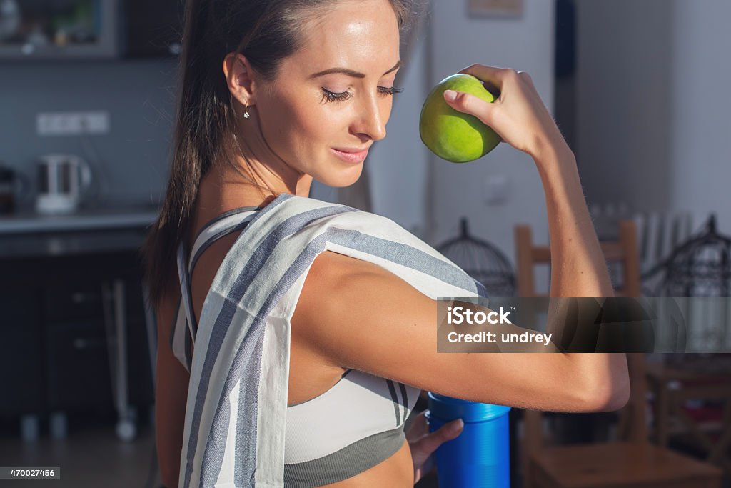 Active athletic sportive woman with towel in sport outfit holding Active athletic sportive woman with towel in sport outfit holding apple showing biceps healthy lifestyle. 2015 Stock Photo