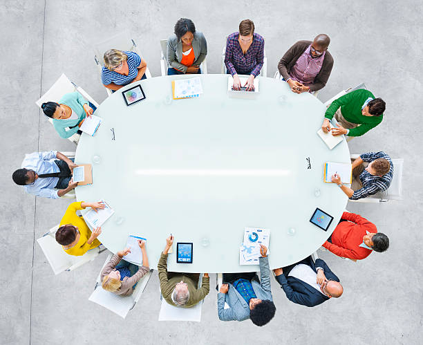 istock People in bright clothing sat around oval conference table 470032490