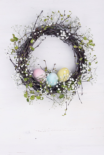 Spring wreath with Easter eggs on a white wooden background. With retro filter effect