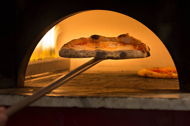Taking Pizza out of Oven stock photo
