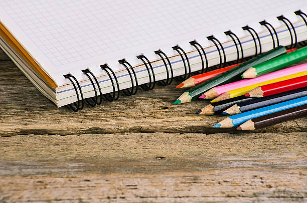 istock Checked blank notebook with multicolored pencils on wood background 470044020