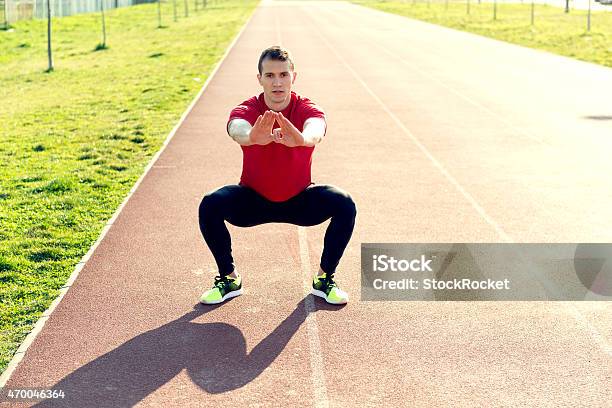 Male Athlete Doing Squats On Track Stock Photo - Download Image Now - 2015, Activity, Adult