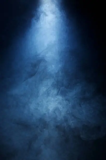 Narrow beam of light passing through blue/grey smoke on a black background. Great used as a dramatic overlay texture or background.