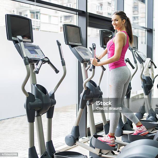 Smiling Woman Exercising On Cross Trainer In A Health Club Stock Photo - Download Image Now