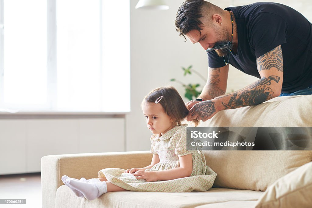 Doing hair for preschool Young father doing little daughter's hair Tattoo Stock Photo