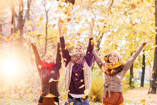istock Playful friends throwing leaves in autumn park. 470062228