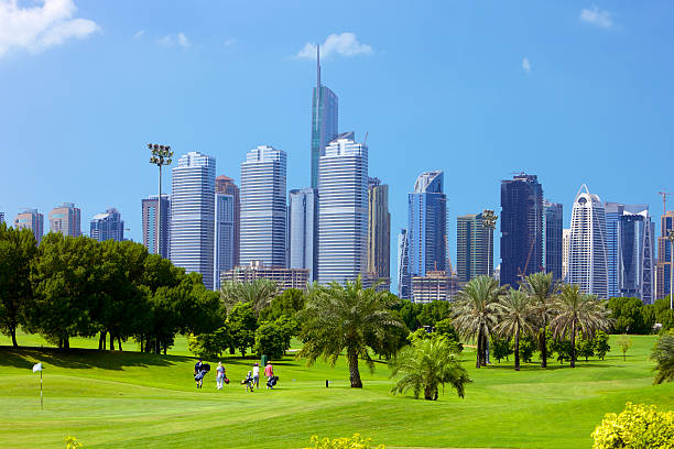 Dubai, United Arab Emirates: A Family Of Golfers On A Well Maintained Fairway - Background: Modern Sky Scrapers In Jumeriah Lake Towers. Copy Space. stock photo