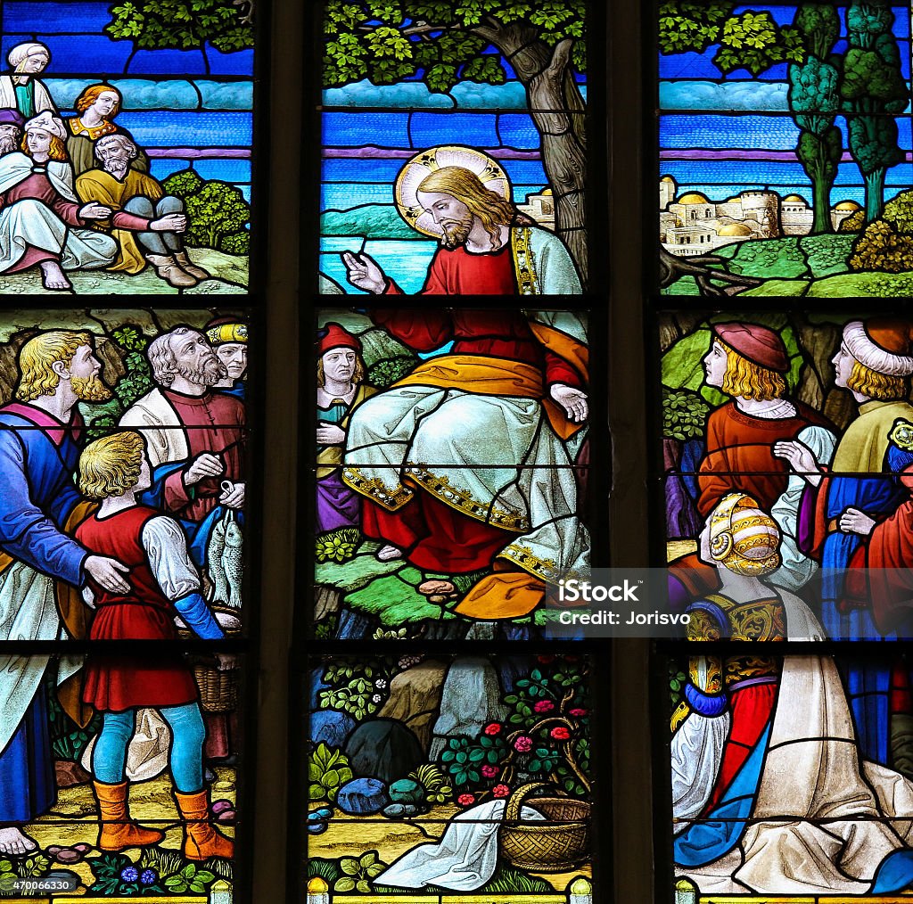 Feeding the multitude Stained Glass window depicting the miracle of Jesus feeding the multitude with loaves of bread and fish in the Cathedral of Saint Rumbold in Mechelen, Belgium.This window was created before 1900, no property release is required. Jesus Christ Stock Photo