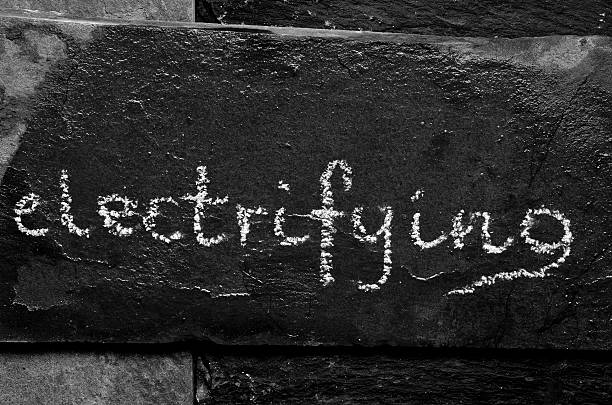 The word ELECTRIFYING written with chalk on black stone.