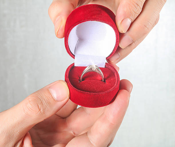 istock Man's hand holding engagement ring isolated on white 470070088