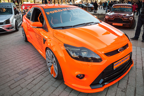 Saint-Petersburg, Russia - April 11, 2015: Bright orange sporty styled Ford focus car stands parked on the street. Wide angle closeup photo