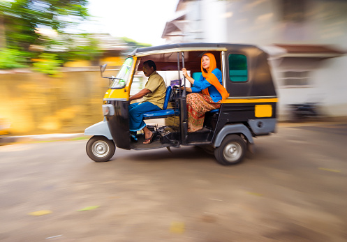 Woman riding a tuk tuk taxi in Fort Cochin, India - panning / motion blur