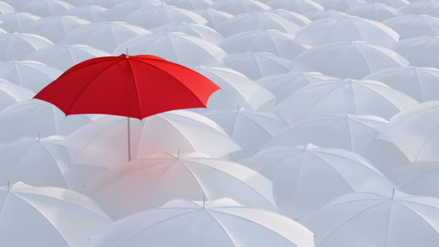 Red umbrella standing out from crowd mass concept