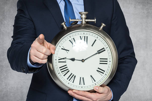 istock businessman with clock pointing at you 470081960