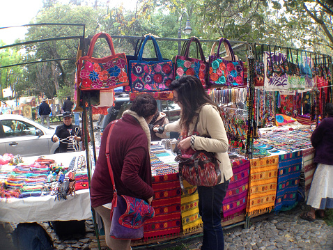 Mexico City, Mexico - February 14, 2015: Two women shopping at one of the many arts and crafts street stalls at the art market in San Angel.