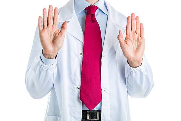 Wait and listen gesture by doctor in white coat Caucasian male doctor dressed in white coat, blue shirt and red tie is making Wait and listen gesture vulcan salute stock pictures, royalty-free photos & images