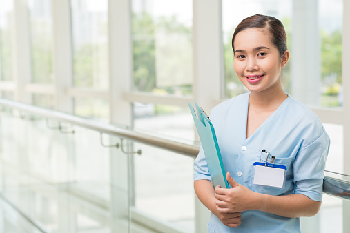 Portrait of smiling Vietnamese nurse with a folder
