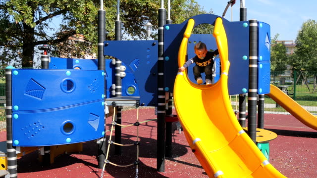 child plays on slide in an outdoor playground