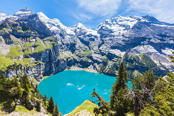 Panorama view of Oeschinensee (Oeschinen lake) on bernese oberla The panorama in summer view over the Oeschinensee (Oeschinen lake) and the alps on the other side near Kandersteg on bernese oberland in Switzerland. lake oeschinensee stock pictures, royalty-free photos & images