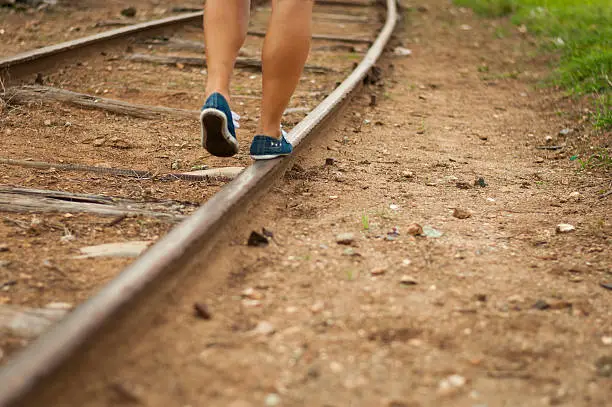 A girl walks over a train trail.