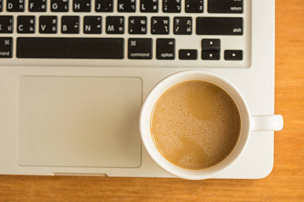 Hot latte coffee cup and laptop on wood background and texture.
