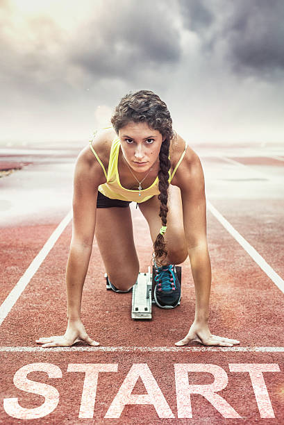 Female athlete with yellow too in the starting blocks Female athlete in the starting blocks forward athlete stock pictures, royalty-free photos & images