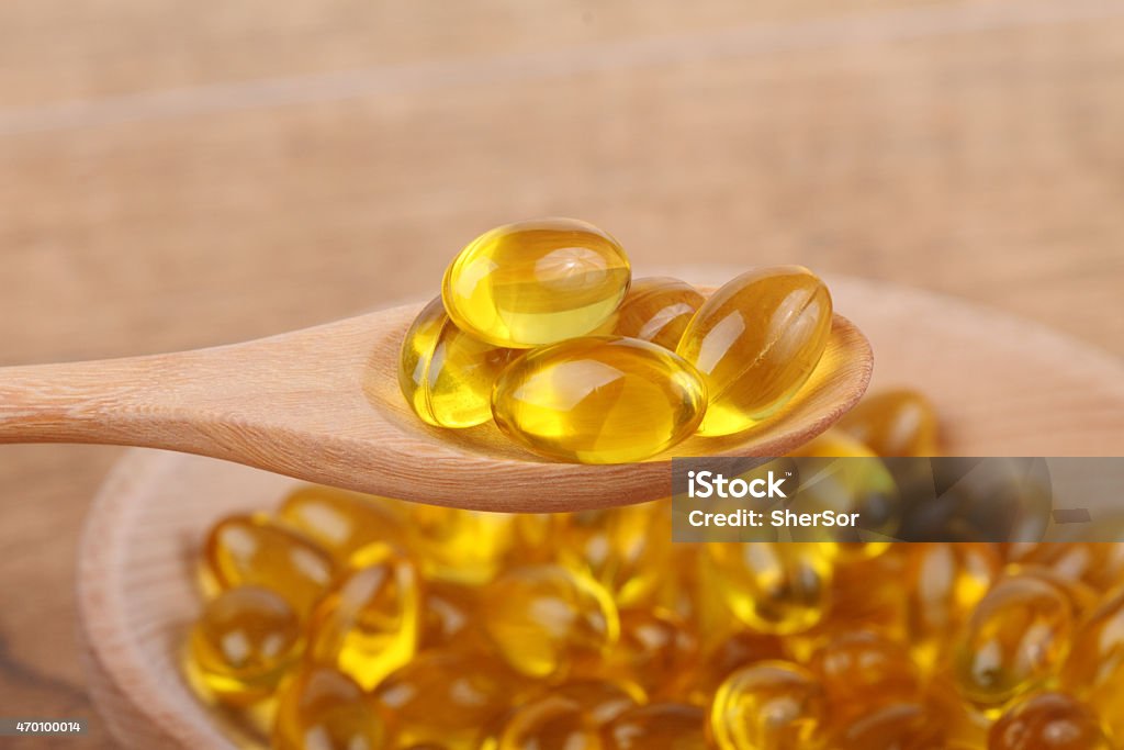 spoon of vitamin capsules Cod liver oil omega 3 gel capsules isolated on wooden background. Vitamin capsules 2015 Stock Photo