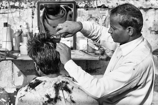 Delhi, India - March 3, 2015. Man getting haircut on the street in Delhi, India.