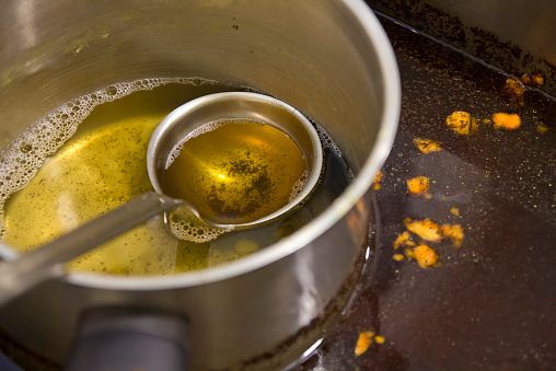 Pot and spoon on a dirty sink in a domestic kitchen.