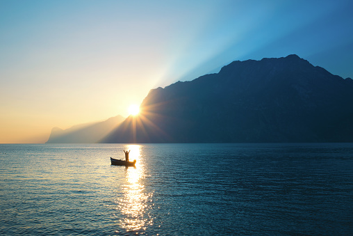 Blissed Man on a canoe exulted under amazing lake view
