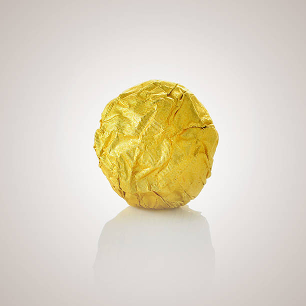 bola de almendras de chocolate en oro con una lámina de papel. - gold carbohydrate food food and drink fotografías e imágenes de stock