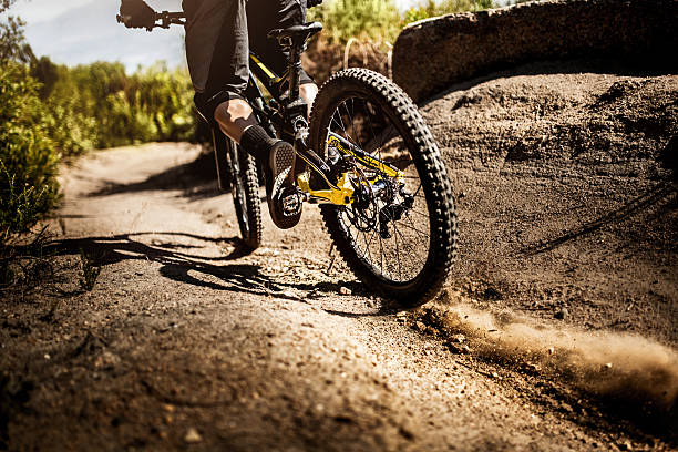 mountain bike riding on carretera de tierra representarlas de la banda de rodadura - dirt stunt fotografías e imágenes de stock