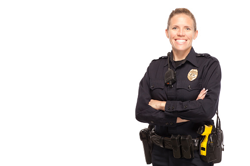 Female police officer posing with arms crossed against white background