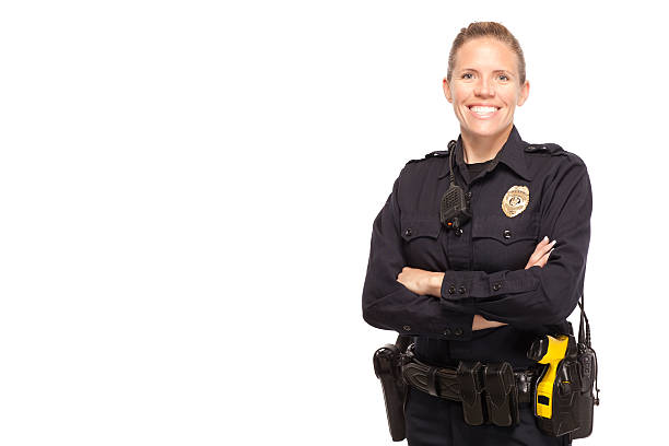 Lady police officer posing with arms crossed Female police officer posing with arms crossed against white background police force smiling officer stock pictures, royalty-free photos & images