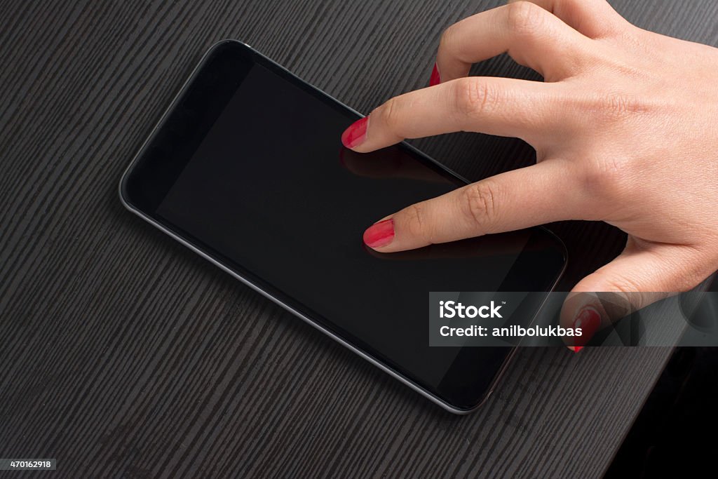 Holding 5.5inch Smartphone A Woman's Hand Holding 5.5inch Black Smartphone front of a laptop. 2015 Stock Photo